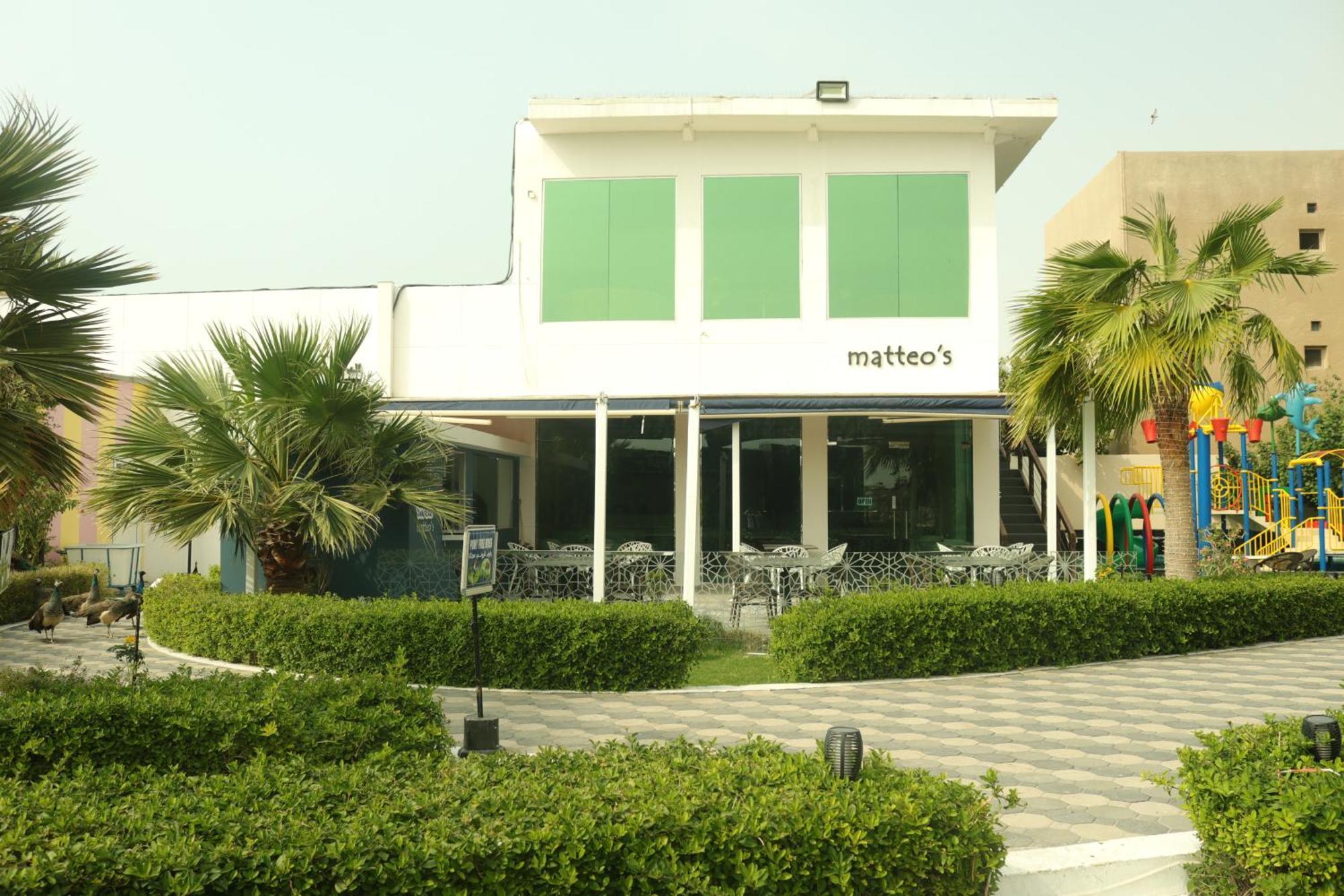 Lagoona Beach Luxury Resort And Spa Manáma Exteriér fotografie The photo shows a building with the name "matteo's" displayed prominently on the front. The structure features large windows and green shutters. There is a landscaped area in front with bushes and palm trees, along with a paved pathway leading up to 