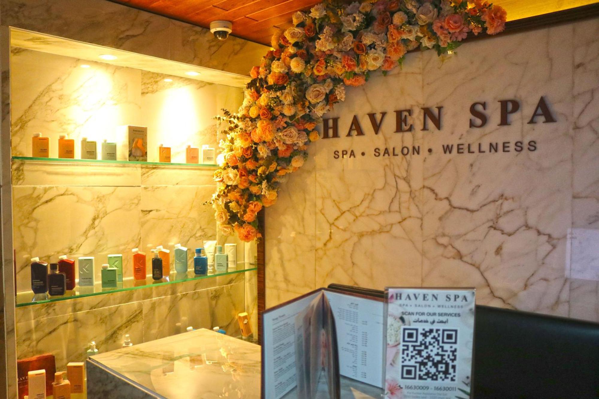 Lagoona Beach Luxury Resort And Spa Manáma Exteriér fotografie The photo shows the interior of a spa called "Haven Spa." The wall is decorated with beautiful artificial flowers, creating an inviting atmosphere. There are several shelves displaying various colorful bottles and products, likely for skincare or wel