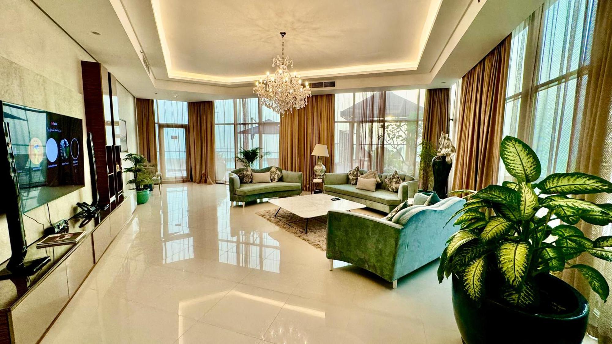 Lagoona Beach Luxury Resort And Spa Manáma Exteriér fotografie The photo depicts a spacious and elegantly designed living room. The room features large windows allowing natural light to flood in, accompanied by sumptuous curtains. The furniture includes a pair of soft green sofas and a centerpiece coffee table s