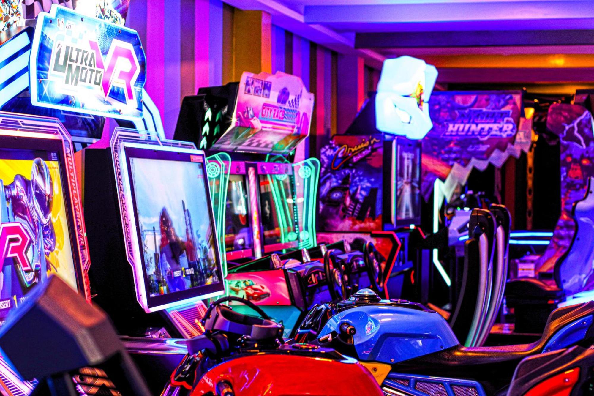 Lagoona Beach Luxury Resort And Spa Manáma Exteriér fotografie The photo shows a vibrant arcade scene featuring various arcade gaming machines. The machines are lined up, showcasing colorful screens and bright, neon lights, creating an energetic atmosphere. Some machines appear to be racing games, as indicated b