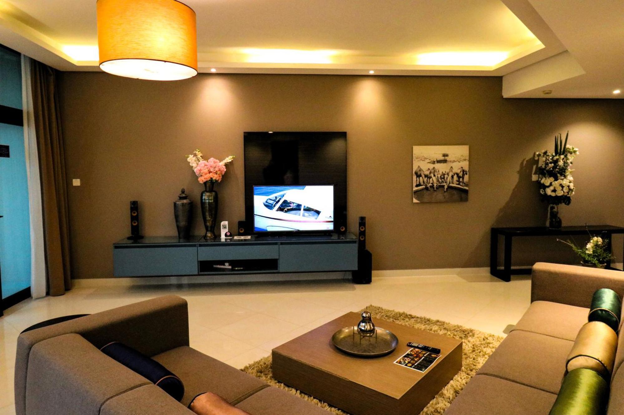 Lagoona Beach Luxury Resort And Spa Manáma Exteriér fotografie The photo shows a modern living room with a neutral color palette. Key features include:

- A comfortable seating area with a sofa arranged around a coffee table.
- A minimalist coffee table with a decorative item on top.
- A large flat-screen televi