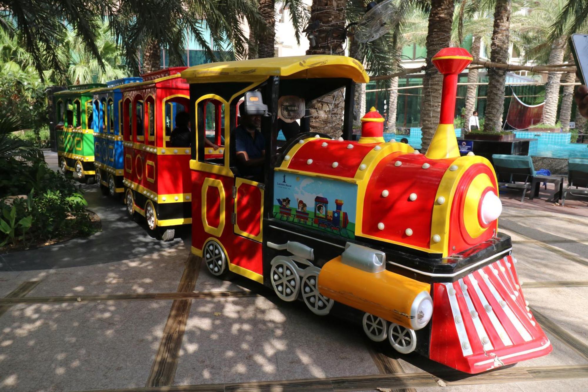 Lagoona Beach Luxury Resort And Spa Manáma Exteriér fotografie The photo shows a colorful miniature train. It features a vibrant design with bright red, yellow, and blue colors. The front of the train resembles a classic steam engine, complete with a prominent smokestack. The train is designed to resemble a fun 